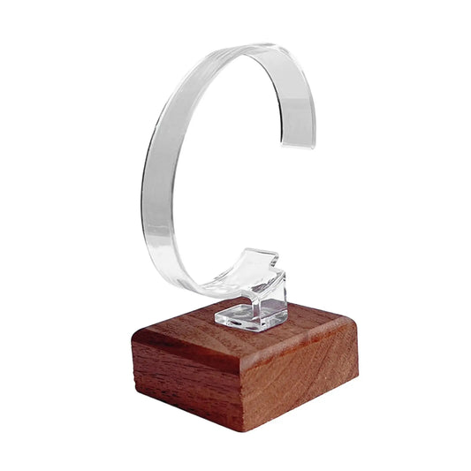 Clear ring holder on a wooden base with a white background