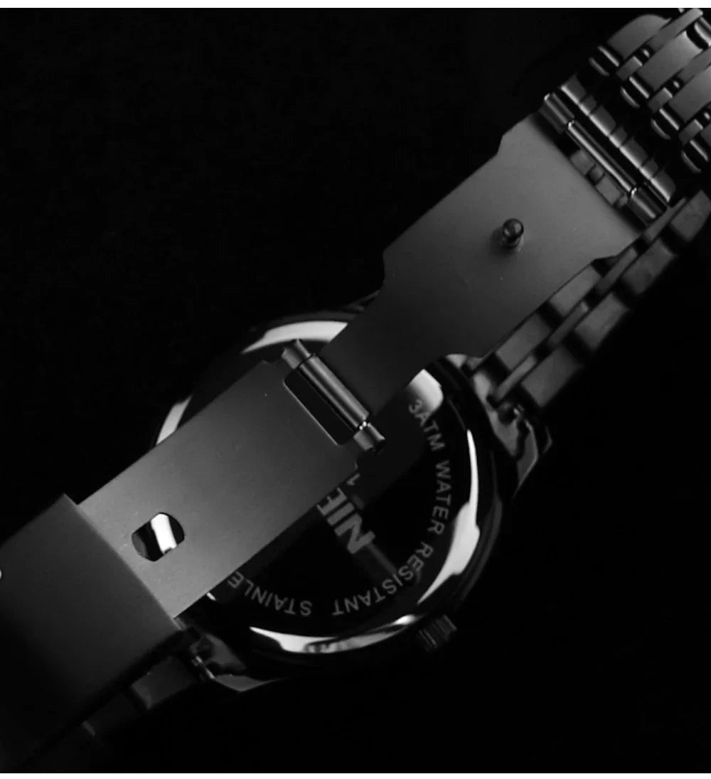 Close-up of a black wristwatch with metal strap on a dark background