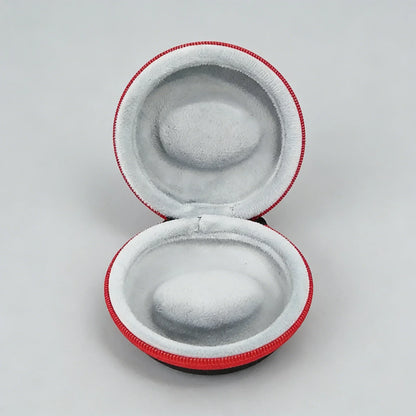 Round gray earbud case with red trim on a light gray background
