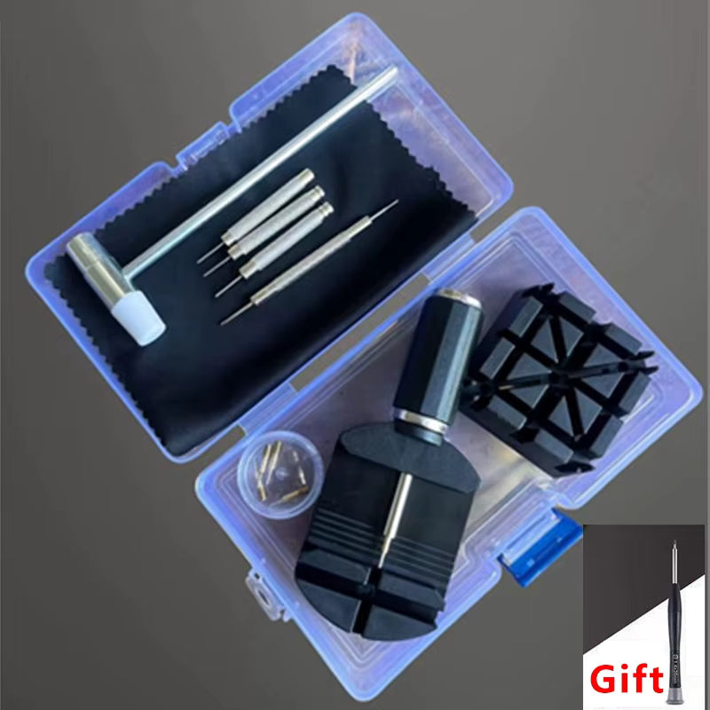 A watch or instrument repair kit shown open on a dark gray background, with multiple metal screwdriver bits, a small hammer, a black cleaning cloth, small screws, and a black plastic stand inside a translucent plastic case. A small 'Gift' label appears in the bottom-right corner.