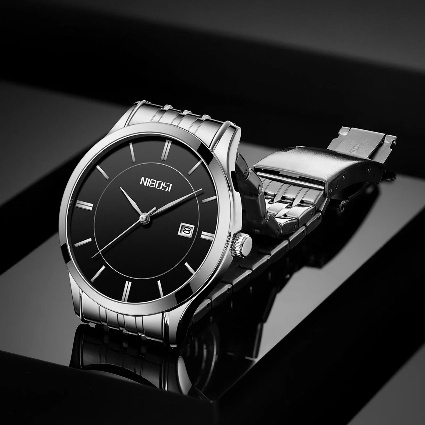 Silver watch with black face on a reflective black surface