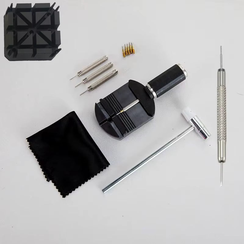 A jewelry making tool kit laid out on a white background, including a black ring press, silver-toned screwdrivers, a textured metal rod, a black cloth, a small black stand, and a black-and-silver mallet.