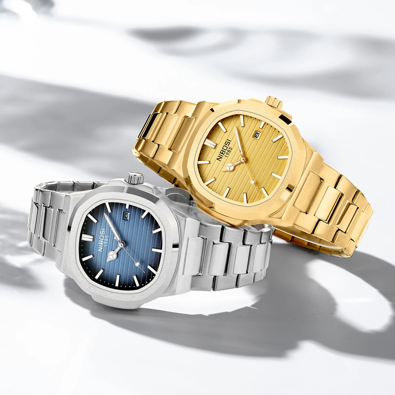 Two watches, one gold and one silver, on a light background
