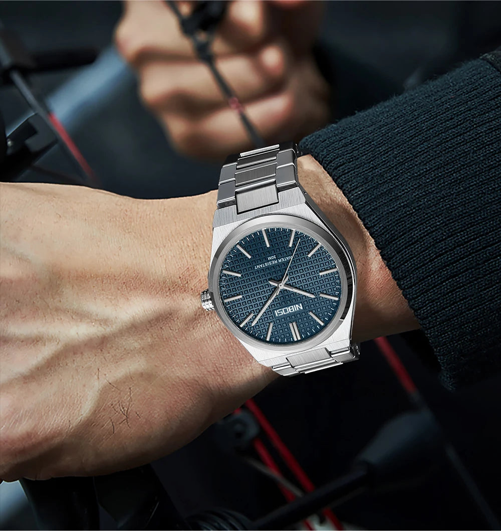 Silver watch with blue dial on a person's wrist, blurred background