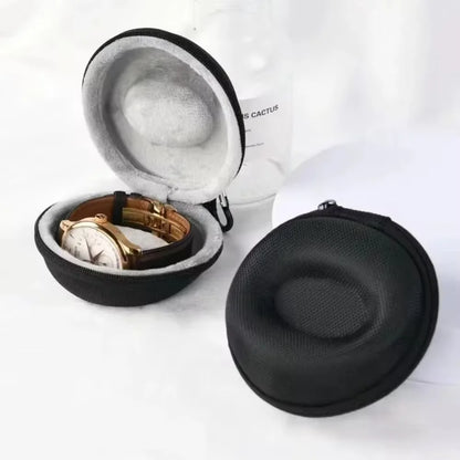 Black hard-shell travel case with a watch inside on a white background