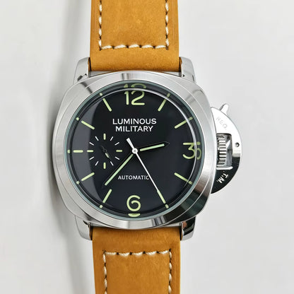 A close-up of a wristwatch with a tan leather strap, a silver-tone case, and a black dial featuring luminous green numerals and hands. The text 'LUMINOUS MILITARY' is visible on the dial.