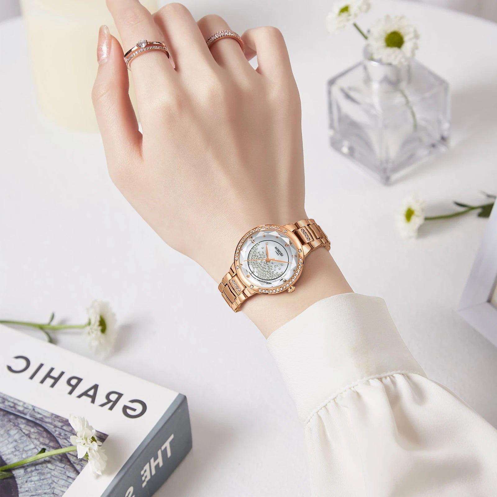 Hand wearing a rose gold watch with a white background