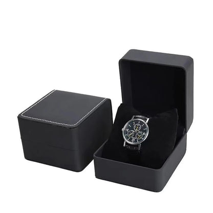 Black watch box with a silver watch inside on a white background