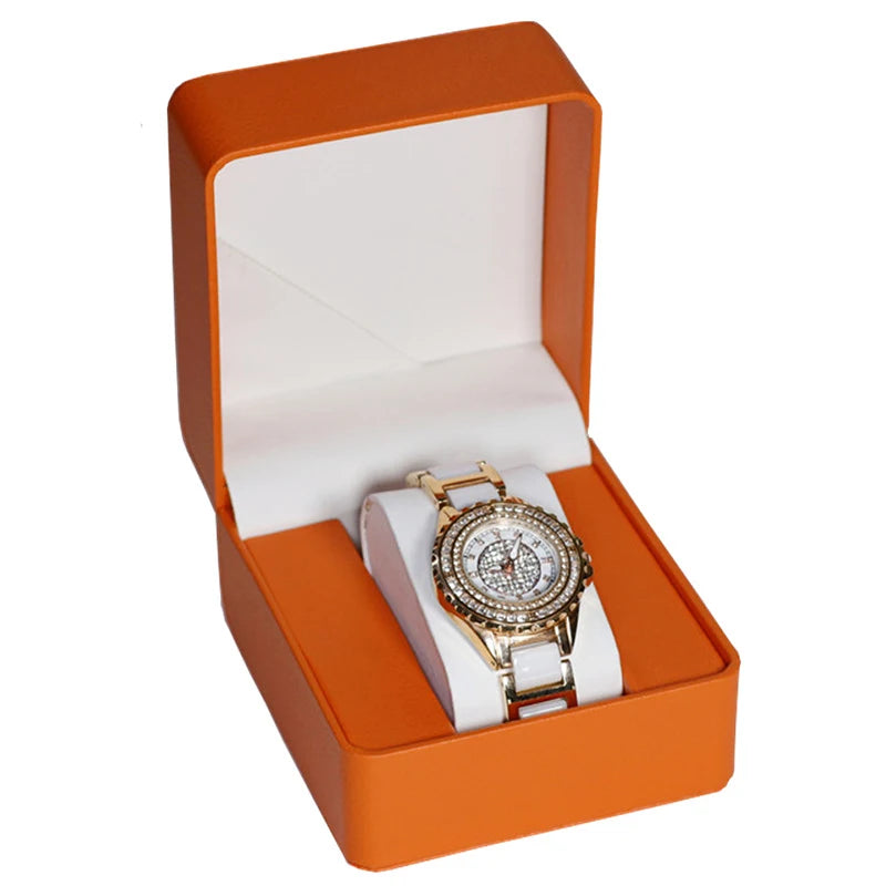 Gold watch with white strap in an orange box on a white background